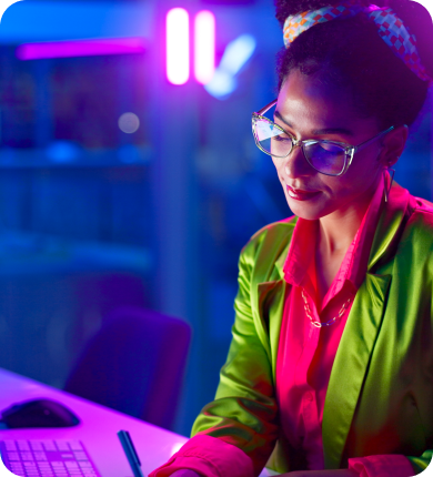 Una mujer con una chaqueta verde, concentrada en su computadora, participando en actividades de trading de forex.