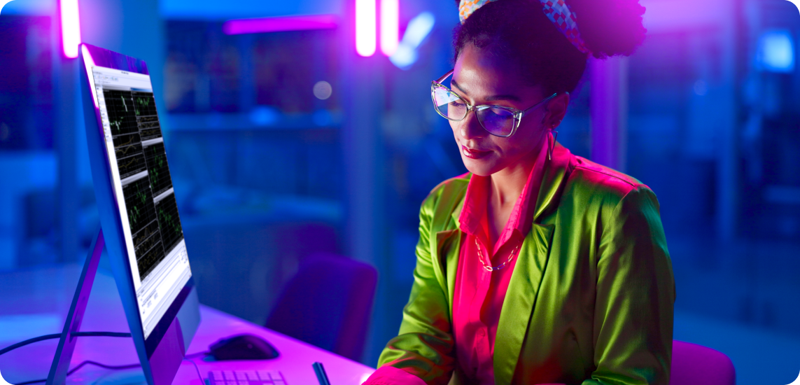 Una mujer con una chaqueta verde, concentrada en su computadora, participando en actividades de trading de forex.