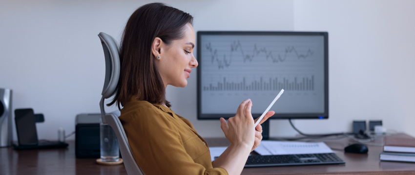 Una mujer en su escritorio, usando una tableta, ejemplificando a una trader fundamental en acción.